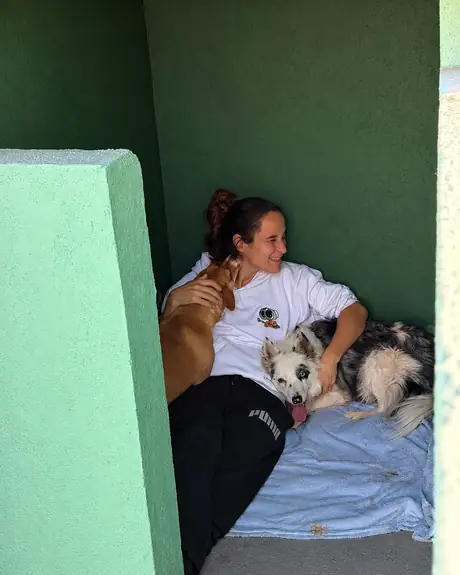Veterinária deitada sobre uma manta com dois cães, um caramelo e um preto e branco