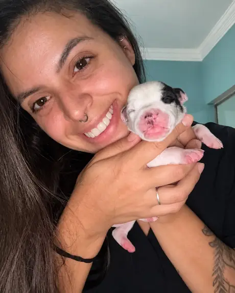 Veterinária sorrindo com um filhote recém-nascido nas mãos